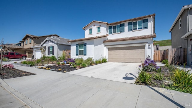 view of front of property featuring concrete driveway, a tiled roof, fence, a garage, and stucco siding