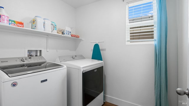 washroom with baseboards, washer and clothes dryer, and laundry area