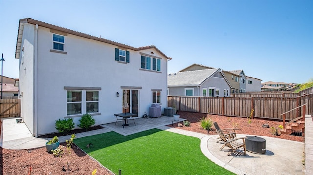 back of property with a fenced backyard, a yard, a patio, and stucco siding