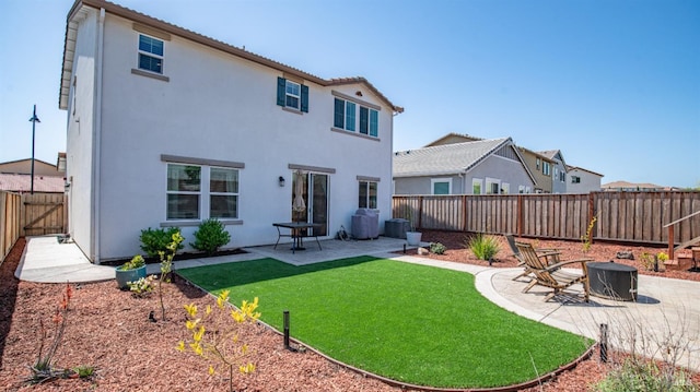rear view of property with stucco siding, a lawn, a fenced backyard, and a patio
