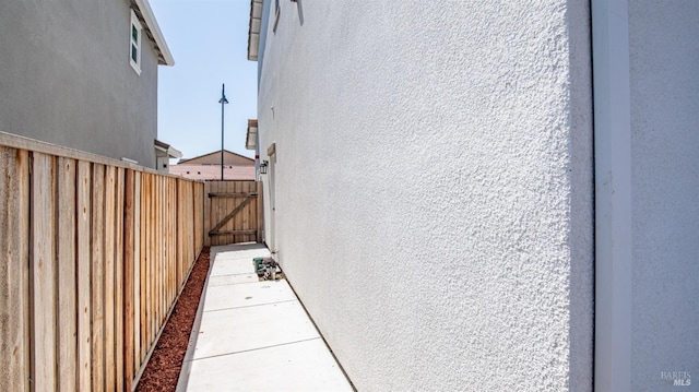 view of side of property with stucco siding, a gate, and fence