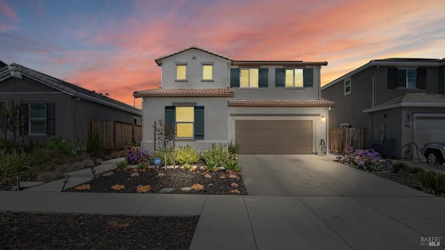 view of front of property with an attached garage, a tile roof, driveway, and fence