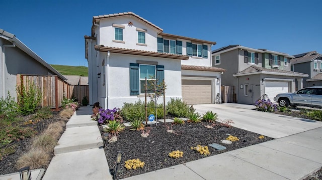 mediterranean / spanish-style home featuring fence, stucco siding, an attached garage, a tile roof, and driveway