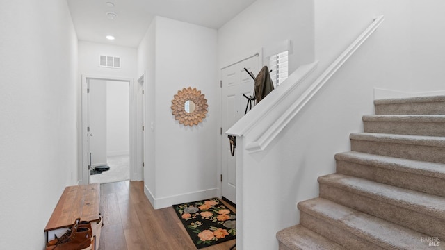 foyer featuring wood finished floors, stairs, baseboards, visible vents, and recessed lighting