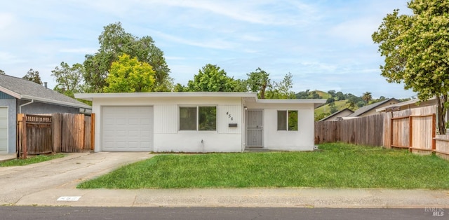 single story home with an attached garage, a front lawn, fence, and concrete driveway