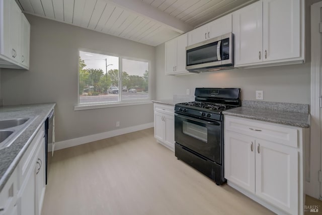 kitchen with white cabinetry, stainless steel microwave, light wood-style floors, and black range with gas stovetop