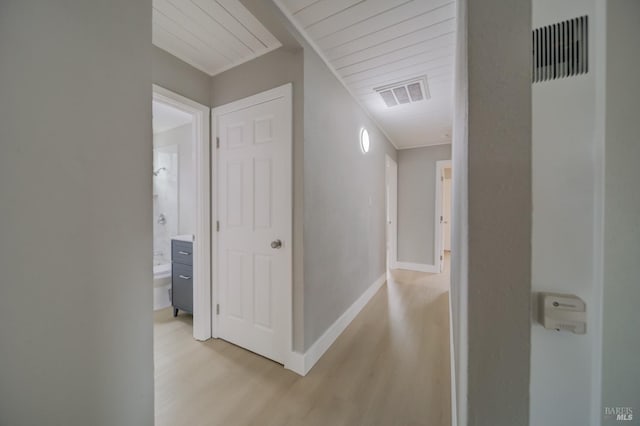 corridor featuring baseboards, visible vents, and light wood finished floors