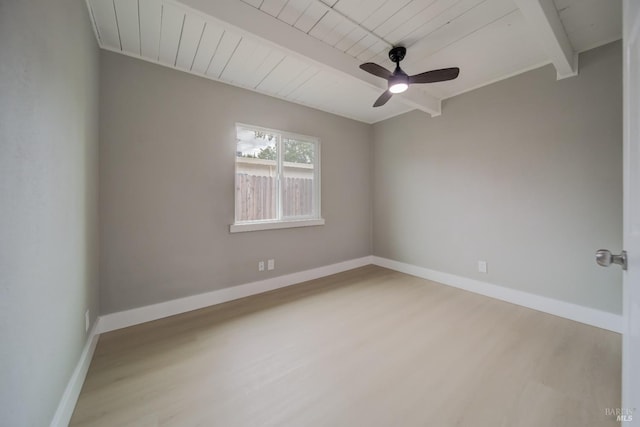 empty room featuring baseboards, a ceiling fan, wood finished floors, and beam ceiling