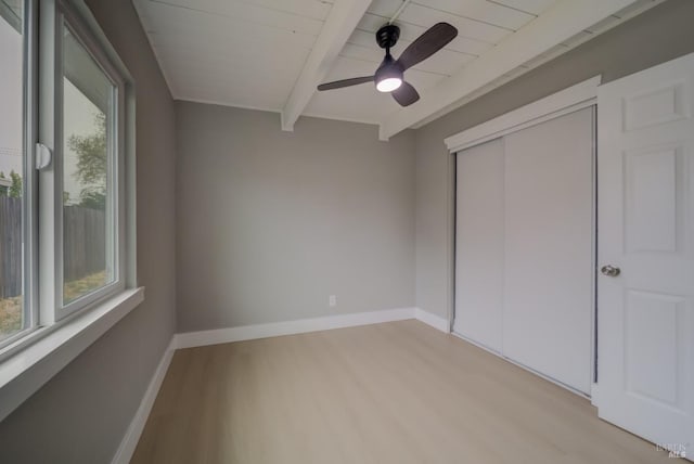 unfurnished bedroom featuring beam ceiling, light wood-style floors, a ceiling fan, wooden ceiling, and a closet