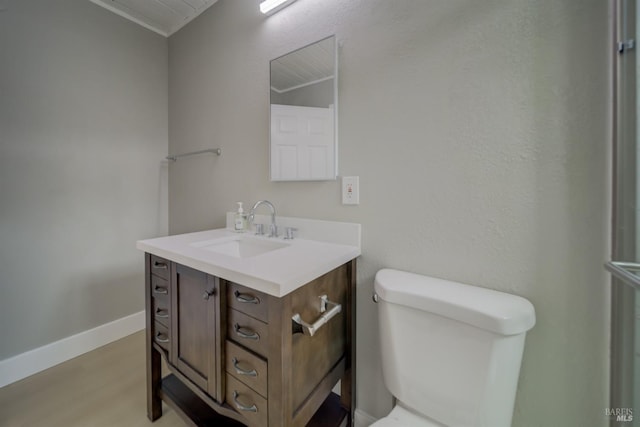 half bathroom with vanity, baseboards, toilet, and wood finished floors