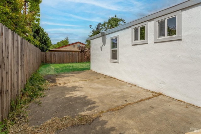 view of property exterior with a fenced backyard, stucco siding, and a patio area