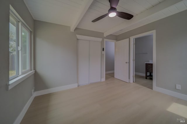unfurnished bedroom featuring light wood-style floors, baseboards, and beamed ceiling