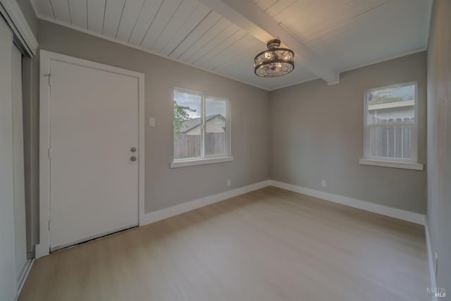 interior space featuring baseboards, plenty of natural light, beam ceiling, and wood finished floors