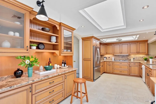 581 Werner Way, Vacaville, CA 95688 - kitchen with freestanding refrigerator, tasteful backsplash, a skylight, light stone countertops, and light tile patterned floors