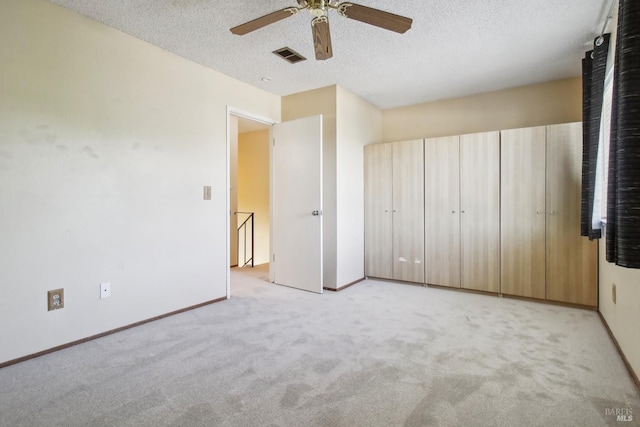 unfurnished bedroom with light carpet, a textured ceiling, visible vents, and baseboards