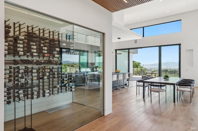 wine area with visible vents, plenty of natural light, wood finished floors, and a towering ceiling