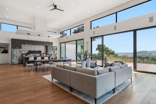 living room featuring a wealth of natural light, light wood finished floors, and a towering ceiling