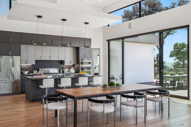 dining room with a towering ceiling, wood finished floors, and a wealth of natural light