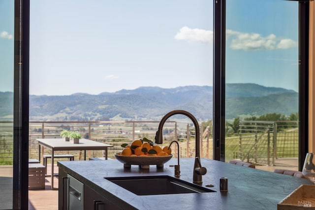 kitchen featuring dark stone counters, a mountain view, and a sink