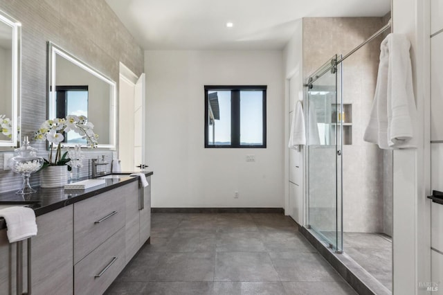 bathroom with baseboards, decorative backsplash, a stall shower, and vanity