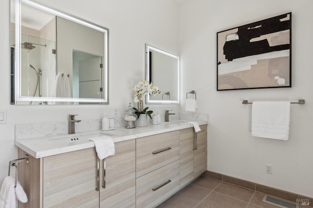 full bath featuring double vanity, baseboards, a sink, and tile patterned flooring