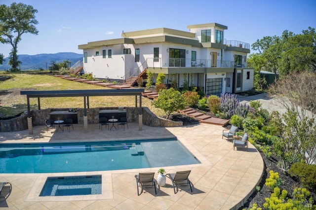 back of property featuring a mountain view, an outdoor pool, stairs, and stucco siding