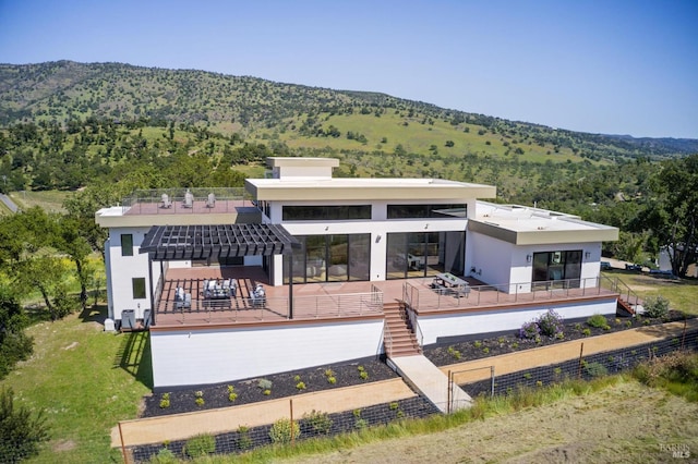 rear view of property with a mountain view, stucco siding, and fence