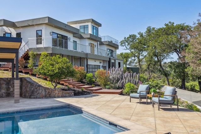 rear view of property featuring stairway, a patio, an outdoor pool, and stucco siding