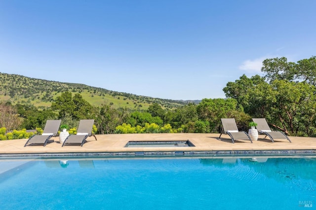 outdoor pool featuring a patio and an in ground hot tub