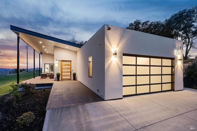 modern home with a garage, outdoor lounge area, stucco siding, and concrete driveway
