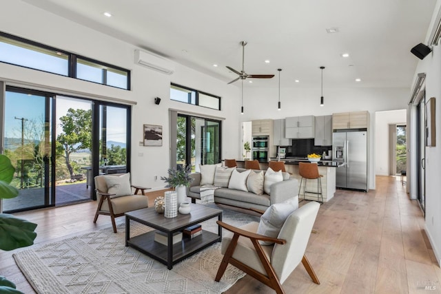living area featuring a high ceiling, a wall mounted AC, a ceiling fan, and recessed lighting
