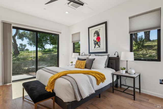 bedroom with hardwood / wood-style floors, baseboards, multiple windows, and access to outside
