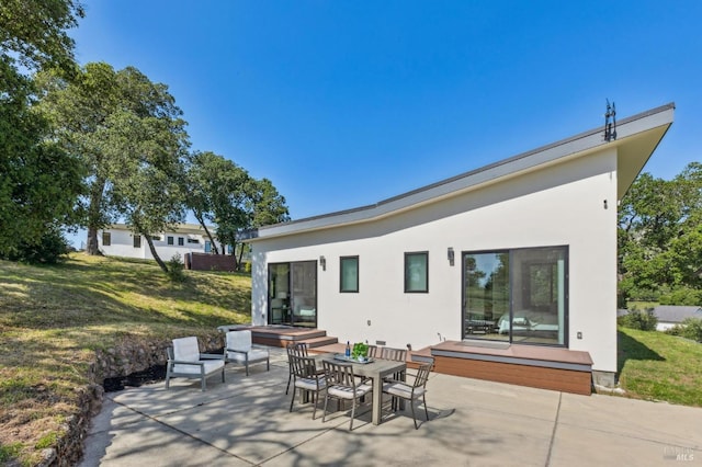 back of property with a patio area, stucco siding, and a yard