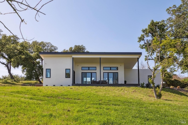 rear view of property featuring a lawn and stucco siding