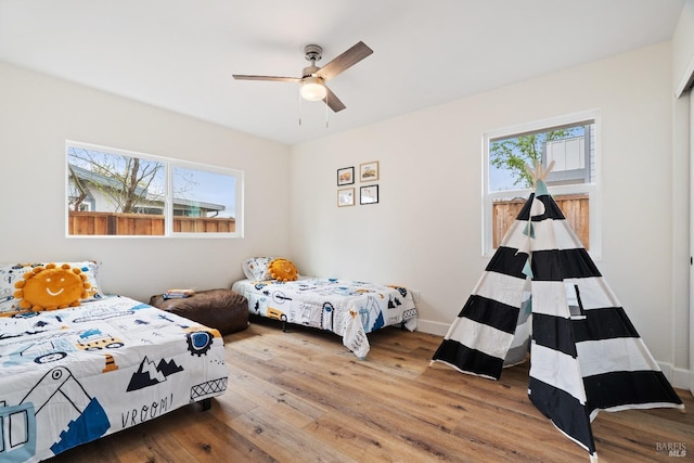bedroom with baseboards, wood finished floors, and ceiling fan