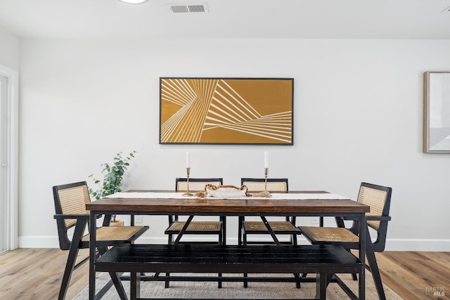 dining room featuring light wood-style floors, visible vents, and baseboards