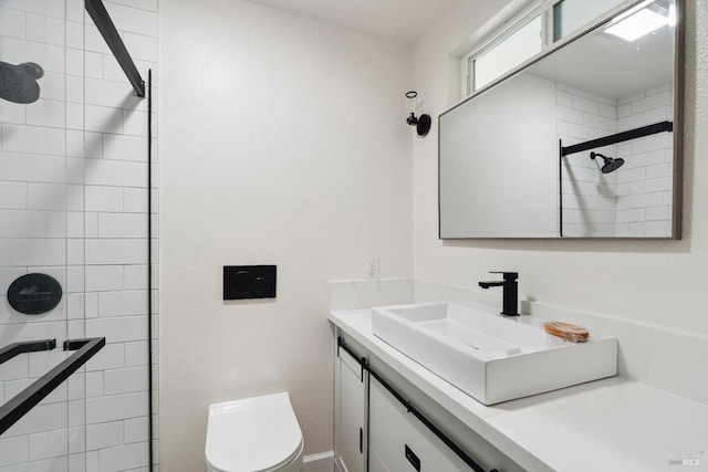 bathroom featuring toilet, vanity, and tiled shower