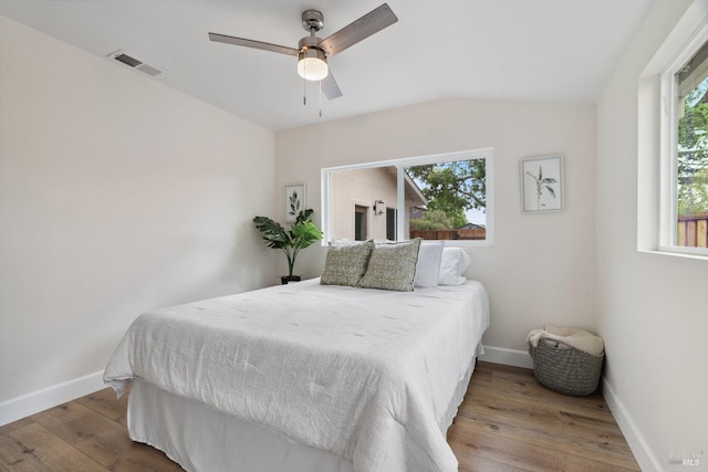 bedroom with baseboards, a ceiling fan, visible vents, and wood-type flooring