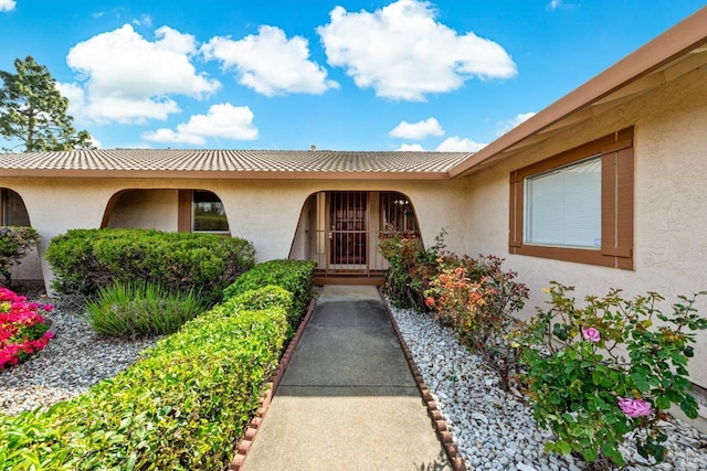 doorway to property with a tile roof and stucco siding