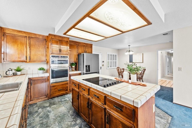 kitchen with stainless steel appliances, a sink, visible vents, brown cabinets, and tile countertops