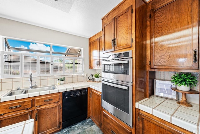 kitchen with stainless steel double oven, dishwasher, brown cabinetry, a sink, and tasteful backsplash