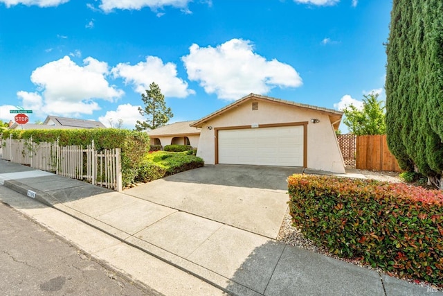 ranch-style house featuring stucco siding, fence, driveway, and a garage