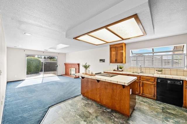 kitchen with tile counters, a sink, black appliances, open floor plan, and a brick fireplace