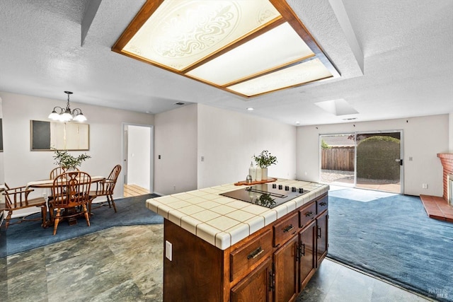 kitchen with a center island, carpet flooring, a textured ceiling, black electric stovetop, and tile counters