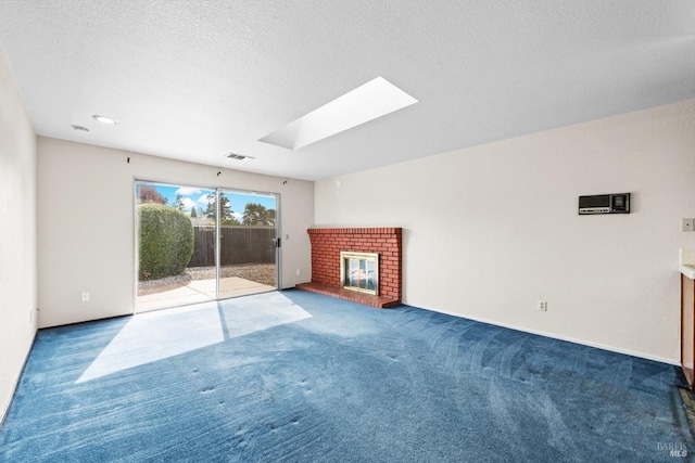 unfurnished living room with visible vents, a skylight, a fireplace, a textured ceiling, and carpet flooring