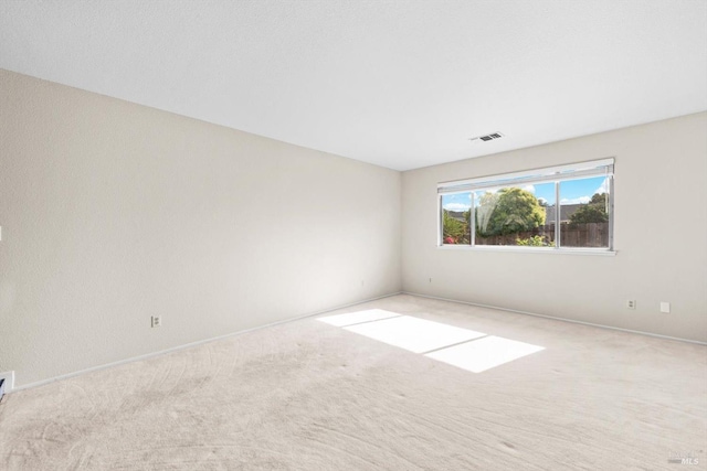 carpeted spare room featuring visible vents and baseboards