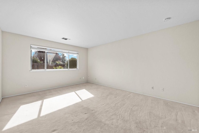 spare room featuring carpet floors, visible vents, and baseboards