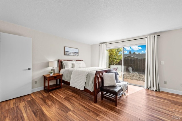 bedroom featuring a textured ceiling, wood finished floors, access to exterior, and baseboards