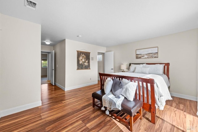 bedroom with baseboards, wood finished floors, and visible vents
