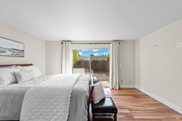 bedroom with baseboards, access to outside, wood finished floors, and a textured ceiling